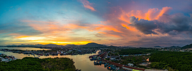 Wall Mural - A breathtaking view of a vivid yellow, pink and purple sunset reflecting on calm sea. This serene scene captures the beauty of nature's colors at Phuket fishing port. colorful cloud scape background