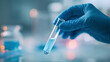 © Zanna - Scientist’s hand in blue nitrile glove holding a transparent test tube with liquid – close-up in laboratory environment, concept of medical research, analysis, or biotechnology
