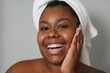 © Sabrina - Happy curvy african girl smiling on camera during skin care routine - Young woman, beauty treatment and wellness concept