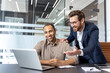 © Liubomir - Two business colleagues smiling while looking at a laptop in an office setting, showing teamwork and collaboration.