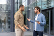 © Liubomir - Two men engaged in a heated discussion outside a modern building, possibly a workplace conflict