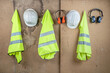 © Rafa Jodar - High visibility vests, hard hats and protective earmuffs hanging on wall as PPE for safety at construction site.