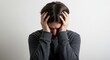 © Kickit - A person with their head in hands, showing signs of distress and worry.