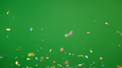 Dynamic burst of colorful confetti exploding upwards on a vibrant green background, party celebration