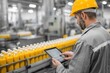 © Iftikhar alam - Worker in production facility uses tablet to monitor bottling process of orange juice during daytime operations
