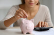 © UniqGraphicX - Woman putting a coin into piggy bank for future savings, financial investment and retirement