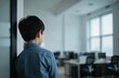 © Oleksandr - Asian child in blue shirt stands back to camera in modern office. AI generated image shows kid looking out large window. Focus on child solitary presence in empty workspace.