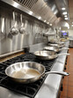 © SashaMagic - Stainless steel frying pans on a professional restaurant stove.