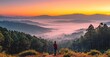 © Aan - Person stands on mountaintop at sunrise, looking over misty valley