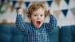 © Ilona - A young child joyfully celebrates an occasion with raised fists and an excited expression. The room is decorated with festive bunting, creating a warm atmosphere