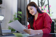 © SOMKID - business woman working on laptop with paper document at office.