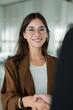 © Andrii Zastrozhnov - Smiling hispanic young woman in glasses shaking hands indoors