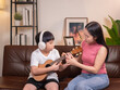 © Oil And Den - Family: Mother or sister with son or brother playing ukulele, singing in the living room.