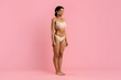 © Anastasiya - Smiling young African American woman in stylish beige underwear standing in studio on pink background, joyful and confident. Healthy and empowering fashion and body image visual, copy space
