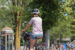 © 24K-Production - A person rides a bicycle in a vibrant urban park, enjoying the sunshine and greenery on a warm day.