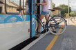 © 24K-Production - A cyclist prepares to board a train with a bicycle at a busy station during daytime, showcasing sustainable transport.