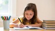 © Darya - Focused child doing homework at home with school supplies on wooden table