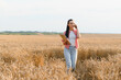 © Serhii - Farmer walking through wheat field while talking on smartphone and holding tablet