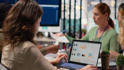 Poster - focused businesswoman analyzing graphs and data on laptop at the table, working with determination and strategic thinking. Aligning corporate objectives with performance indicators. Camera B.