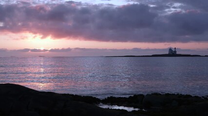 Wall Mural - dramatic coastal sunset behind hestskjaeret lighthouse, silhouetted on the horizon off averoya