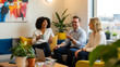 © True Stock - Group of three Asian coworkers laughing together in casual creative office corner showing joy and workplace culture
