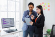 © David - Two asian coworkers standing in the office discuss about business plan and looking at tablet.handsome asia man and beautiful asian woman as business partners working at indoor