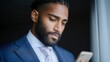 © BOJOShop - Bearded man in a blue suit and tie looks down at his smartphone dark background