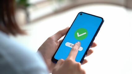 Woman Interacting with Blue Smartphone Displaying Green Checkmark Against a White Background