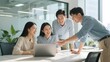 © Big - Four colleagues collaborating around a laptop in a modern office setting