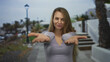 © Krakenimages.com - Woman pointing camera outdoors showing confidence street city background wearing casual grey shirt smiling afternoon light urban scene.