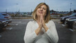 © Krakenimages.com - Woman clasps hands with closed eyes in street parking lot while gently smiling at parked cars; hope.