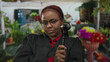 © Krakenimages.com - Woman judge holds gavel in raised hand outside vibrant flower shop on busy street; justice authority.