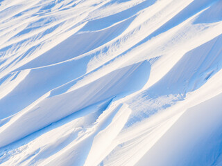 Wall Mural - Snow texture. Wind sculpted patterns on snow surface. Wind in the tundra and in the mountains on the surface of the snow sculpts patterns and ridges (sastrugi). Arctic, Polar region. Winter background