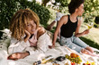 © Bliss - Friends enjoying a sunny picnic with delightful snacks in the park during summer