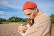 © DimaBerlin - Man lovingly kisses wraps arms around frightened cat burrowing muzzle into hands during beach walk. Affectionate protective embrace for scared pet, comfort giving, relieving fear, travel companionship