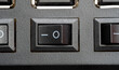 © Tomasz - Macro top view of an io rocker power switch in the on position, black plastic button on a generic electronic device panel, closeup of a hardware control used to start or shut down equipment appliance