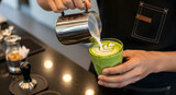 Barista pouring milk to create latte art in a matcha drink