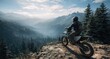 © twobrother - A lone motorcyclist sits atop a rocky cliff overlooking a vast, misty mountain valley shrouded in evergreen forests and snow-capped peaks under a bright, partly cloudy sky