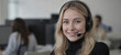 © Pete - Smiling woman with blonde hair wears headset, black turtleneck, looking at camera in office setting. Represents customer service, tech support, remote work professional. Positive interaction,