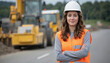 © Pete - Confident woman engineer smiles, arms crossed, at road construction site. Wearing hard hat, safety vest. Heavy machinery, asphalt visible. Represents expertise, leadership, and industry professions.