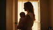 © AlexanderVP - Young woman holding baby in silhouette by window at home