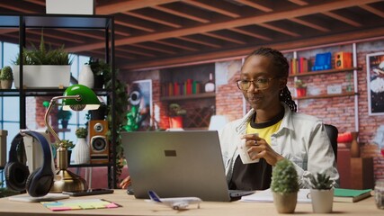 Poster - Remote worker at home office desk drinking coffee and browsing internet on notebook, researching information. Woman enjoying hot beverage while using search engines to find data for work, camera A