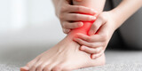 Woman holding ankle with subtle red pain highlight, realistic close-up

