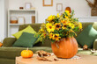 © Pixel-Shot - Pumpkins with flowers and fallen leaves on table in living room