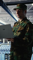 Poster - Vertical video Soldier in server hub using laptop to deploy AI tech, modernizing defense infrastructure. Military data center specialist integrating artificial intelligence technology using notebook