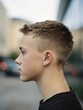 © Anat art - Teenage Boy With Fade Haircut Poses Against Blurred School Background in Urban Setting During Daytime