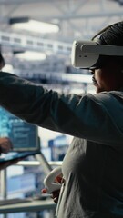 Poster - Vertical video Software developer in server room wearing VR goggles optimizing deep learning systems handling tasks. African american woman in data center adjusts AI model parameters using virtual