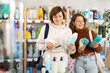 © JackF - Mum with adult daughter purchases household chemicals in store, choose shower gel or shampoo items and body washcloth. Buyer examines product in detail, looking for consumer information on packaging.