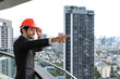 © Jack Tamrong - Handsome Indian businessman wearing safety helmet standing at high rise office balcony