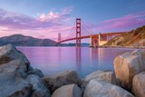 Golden Gate Bridge view orange structure pink sky rocks in foreground